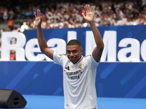 French forward Kylian Mbappe waves to the fans during a first appearance as a Real Madrid player at the Santiago Bernabeu Stadium in Madrid on July 16, 2024, after signing his new five-season contract. Still celebrating Spain's Euro 2024 triumph, Real Madrid fans have even more to cheer this July 16, 2024, as French superstar Kylian Mbappe is officially presented to a packed-out Santiago Bernabeu stadium. (Photo by Pierre-Philippe MARCOU / AFP