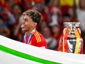 Spain's forward #19 Lamine Yamal reacts next to the trophy after winning the UEFA Euro 2024 final football match between Spain and England at the Olympiastadion in Berlin on July 14, 2024. (Photo by Jewel SAMAD / AFP)