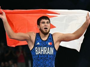 Bahrain's Akhmed Magomed O Tazhudinov celebrates his win with his national flag after beating Georgia's Givi Matcharashvili in their men's freestyle 97kg wrestling final match at the Champ-de-Mars Arena during the Paris 2024 Olympic Games, in Paris on August 11, 2024. (Photo by Punit PARANJPE / AFP)