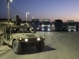 Israeli soldiers sit in an army vehicle near trucks loaded with humanitarian aid delivered from Jordan waiting to cross into Gaza on the border between Israel and the northern Gaza Strip, through the Israeli-controlled Erez crossing on October 21, 2024, amid the ongoing war between Israel and the militant group Hamas. (Photo by Jack GUEZ / AFP)