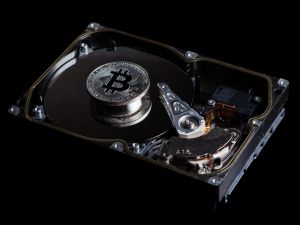 Silver Bitcoin coin on the opened HDD disk