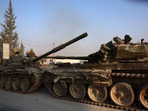Anti-government fighters sit in tanks left behind by Syrian regime forces in Hama