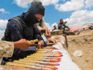 A soldier in an ISIS uniform prepares ammunition