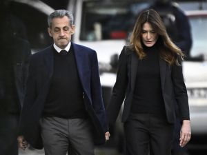 France's former president Nicolas Sarkozy (L), with his wife Carla Bruni-Sarkozy, leaves his residence to present himself to La Sante Prison for incarceration on a five-year prison sentence after being convicted of criminal conspiracy over a plan for late Libyan dictator Moamer Kadhafi to fund his 2007 electoral campaign, in Paris, on October 21, 2025. Sarkozy begins five-year prison term in Paris over Libyan campaign funding scandal