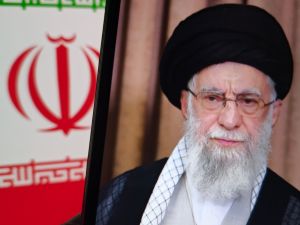 صورة شخصية لآية الله علي خامنئي، المرشد الأعلى لإيران، مع ظهور العلم الإيراني في الخلفية.