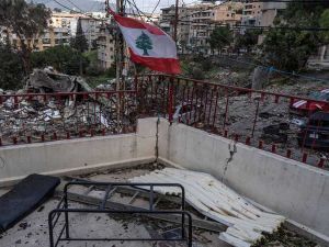 علم لبنان يرفرف فوق مبنى متضرر وسط آثار دمار في منطقة سكنية جنوب البلاد بعد تصعيد عسكري.