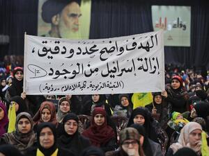 Supporters of Lebanese Hezbollah Leader gather as he delivers a televised speech during a ceremony held by the Shiite party in the capital Beirut, commemorating the party's killed leaders, on Feb. 16, 2018. The writing in Arabic reads: "The goal is clear, specific and precise...the removal of Israel from existence." 
(JOSEPH EID / AFP)
