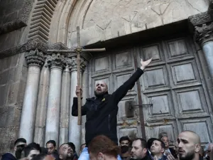 A Palestinian man holds a cross during a protest in front of the Church of the Holy Sepulchre in Jerusalem (AFP/File Photo)