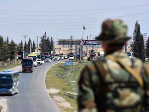 A convoy transporting Jaish al-Islam fighters and their families from the former bastion's main town of Douma arrives at the entrance to the northern Syrian city of Aleppo after being evacuated from the last rebel-held pocket in Eastern Ghouta on Apr. 3, 2018. 
(George OURFALIAN / AFP)