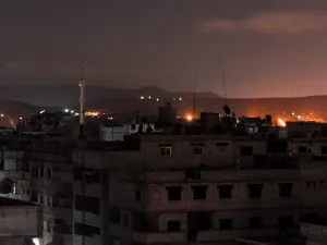 A picture taken early on Apr. 21, 2018 shows explosions appearing in the skyline of a southern district of the Syrian capital Damascus, during regime strikes targeting the Islamic State group in the Palestinian camp of Yarmouk, and neighbouring districts. 
(Rami al SAYED / AFP)