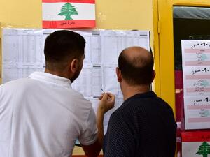 Voters check their names in the voters list at a polling station set up at the Lebanese School (AFP/File Photo)	