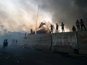 Iraqi protesters wave a national flag while demonstrating outside the burnt-down local government headquarters in the southern city of Basra on September 7, 2018. (Haidar MOHAMMED ALI / AFP)
