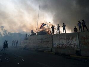 Iraqi protesters wave a national flag while demonstrating outside the burnt-down local government headquarters in the southern city of Basra on September 7, 2018. (Haidar MOHAMMED ALI / AFP)