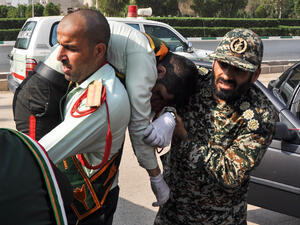This picture taken on September 22, 2018 in the southwestern Iranian city of Ahvaz shows an Iranian soldier carrying an ijured comrade at the scene of an attack on a military parade (AFP)