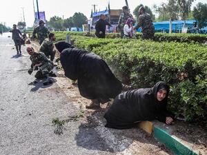 This picture taken on September 22, 2018 in the southwestern Iranian city of Ahvaz shows Iranian women and soldiers taking cover next to bushes at the scene of an attack on a military parade (AFP)