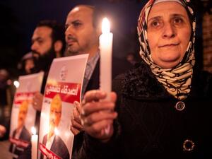 People hold posters picturing Saudi journalist Jamal Khashoggi and lightened candles during a gathering outside the Saudi Arabia consulate in Istanbul, on October 25, 2018. (asin AKGUL / AFP)