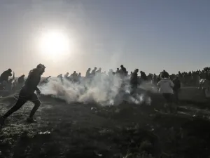 Palestinian protesters run through tear gas fumes during clashes with Israeli forces following a demonstration along the border with Israel east of Gaza City on January 11, 2019. (MAHMUD HAMS / AFP)