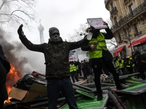 Protesters react as they face police at a barricade during an anti-government demonstration called by the "yellow vests"  (AFP)