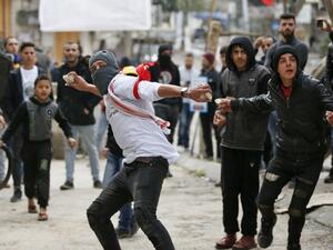 Palestinian protesters hurl stones at Israeli soldiers near a gate leading to Hebron's main al-Shuhada street. (AFP/ File Photo)