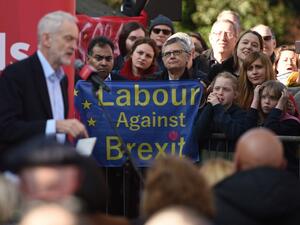 Labour party supporters hold up an anti-Brexit placard as they listen to opposition Labour Party leader Jeremy Corbyn (L) at a rally on February 23, 2019. (AFP/File)
