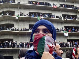 A woman covers her face with the national flag, as Algerian protesters demonstrate in the capital Algiers against ailing president's bid for a fifth term on March 8, 2019. 
RYAD KRAMDI / AFP