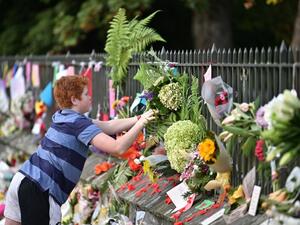 A child leaves flowers in tribute to victims in Christchurch (AFP)