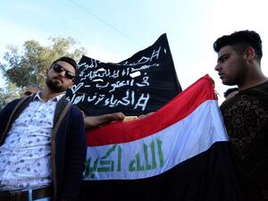Iraqis wave a national flag alongside a banner mourning the victims of a capsized ferry during a vigil in the northern Iraqi city of Mosul on March 22, 2019. (AFP/ File)