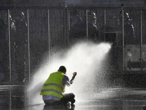 A protester sits on the ground while riot police uses a water cannon during an anti-government demonstration called by the 'Yellow Vest' movement, in Bordeaux, southwestern France, on March 23, 2019. (AFP/ File)