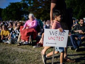 A young boy carries a placard that reads "We Are United" during a vigil held in memory of the twin mosque massacre victims in Christchurch (AFP)