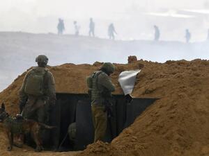Israeli soldiers gather at a position over an earth barrier along the border with the Gaza Strip (AFP)