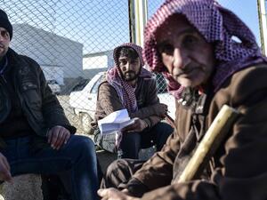 Syrian migrants and refugees wait in front of the Turkish Oncupinar crossing gate, near the town of Kilis, to return to Syria on February 9, 2016. (AFP/Bulent Kilis)
