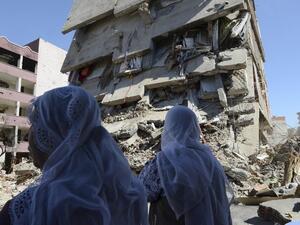 Women walk past the rubble of a damaged building following heavy fighting between government troops and Kurdish fighters in the Kurdish town of Cizre in southeastern Turkey, which lies near the border with Syria and Iraq, on March 2, 2016. (AFP/Ilyas Akengin)