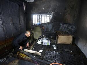 A Palestinian police member inspects the damage inside a burnt-out house belonging to a key witness to an arson attack which took place last year by Jewish extremists that killed a Palestinian family, in the Israeli occupied West Bank village of Duma, after fire broke out in the home in the early hours of March 20, 2016. (AFP/Jaafar Ashtiyeh)