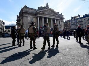 Belgian servicemen stand guard as people gather at the makeshift memorial on the Place de la Bourse Square, in Brussels, on March 27, 2016 to pay tribute to the victims of the Brussels terror attacks which killed 31 people and injured over 300. (AFP/Patrick Stollarz)