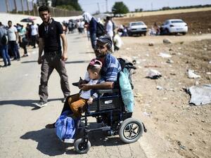 A Syrian refugee on a wheelchair waits on August 28, 2017 at the Oncupinar crossing gate, close to the town of Kilis, south central Turkey, as they wait to cross to Syria for the Eid al-Adha Muslim holiday. Turkish authorities allow Syrian refugees to visit their country for Eid-Al-Adha (Feast of the Sacrifice) celebrities. (AFP)