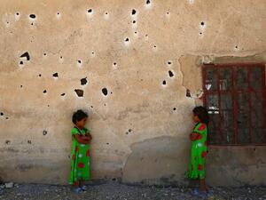 Syrian girls pose for a photograph against a bullet-riddled wall in the rebel-held village of Kafr Ghan, in the northern countryside of Aleppo, on August 28, 2017. (AFP)