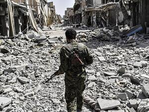 A member of the Syrian Democratic Forces (SDF) sprints through the debris in the old city center on the eastern frontline of Raqqa. (AFP /BULENT KILIC)