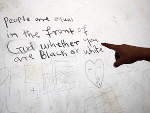 A sub-Saharan migrant shows writings on a wall as he waits at the Qanfouda detention center, in the southern outskirts of Benghazi, before being repatriated on Dec. 2, 2017. 
(Abdullah DOMA / AFP)