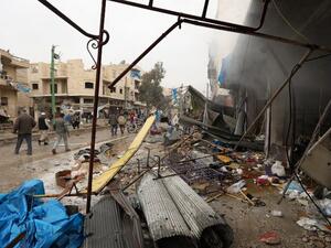 Civilians check the scene of a reported air strike on a market in the city of Maaret al-Numan in Syria's rebel-held Idlib province on Jan. 3, 2018 (OMAR HAJ KADOUR/AFP)