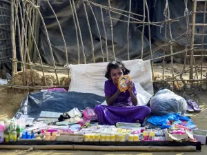 A Rohingya Muslim refugee applies lipstick as she waits for customers at a stall in Kutupalong refugee camp in Bangladesh's Ukhia district on Jan. 12, 2018 (Munir UZ ZAMAN / AFP)