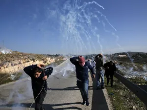 Palestinians run for covers from smoke-grenades during clashes with Israeli security forces following a demonstration in support of Palestinian prisoners on Jan. 13, 2018 (ABBAS MOMANI / AFP)