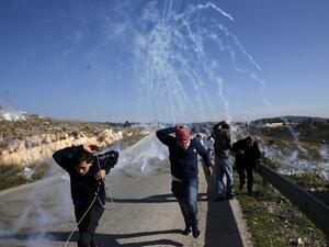 Palestinians run for covers from smoke-grenades during clashes with Israeli security forces following a demonstration in support of Palestinian prisoners on Jan. 13, 2018 (ABBAS MOMANI / AFP)