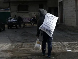 A Palestinian youth carries food donations outside the United Nations food distribution center in Gaza City on Jan. 15, 2018 (MOHAMMED ABED / AFP)