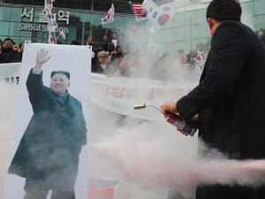South Korean protesters try to burn a picture of North Korean leader Kim Jong-Un during an anti-North Korea rally outside Seoul station in Seoul on January 22, 2018 as a North Korean delegation arrives at the station (YONHAP / AFP)