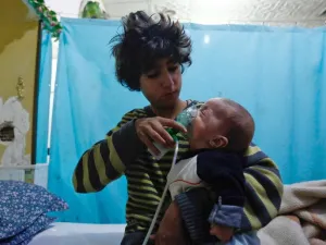 A Syrian boy holds an oxygen mask over the face of an infant at a make-shift hospital following a reported gas attack on the rebel-held besieged town of Douma in the eastern Ghouta region on Jan. 22, 2018 (HASAN MOHAMED / AFP)