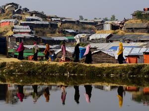 This file photo taken on Nov. 22, 2017 shows Rohingya refugees are reflected on a pond as they walk back to their homes at Balukhali refugee camp in the Bangladeshi district of Ukhia (MUNIR UZ ZAMAN / AFP)