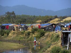 This photo taken on Jan. 23, 2018 shows Rohingya Muslim refugees crossing a canal next to a settlement near the 'no man's land' area between Myanmar and Bangladesh in Tombru in Bangladesh's Bandarban district (Munir UZ ZAMAN / AFP)