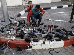 Palestinian charge their mobile phones from batteries, a free service offered in a neighborhood suffering from power cuts, in Gaza City on Feb. 1, 2018 (MOHAMMED ABED / AFP)