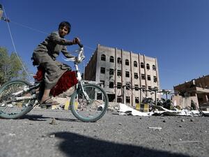 A picture taken on Feb. 5, 2018, shows a child riding his bike next to the Yemeni criminal investigations unit in the capital Sanaa, a day after it was hit in an air raid (MOHAMMED HUWAIS / AFP)