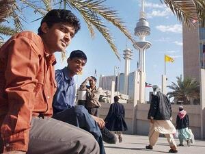 Asian workers take a break after work at a park next to Kuwait's Liberation Tower (AFP/File Photo)